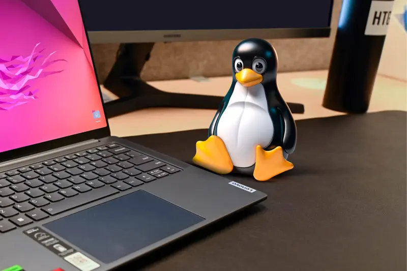 Η μασκότ του Linux σε ένα γραφείο δίπλα σε έναν φορητό υπολογιστή